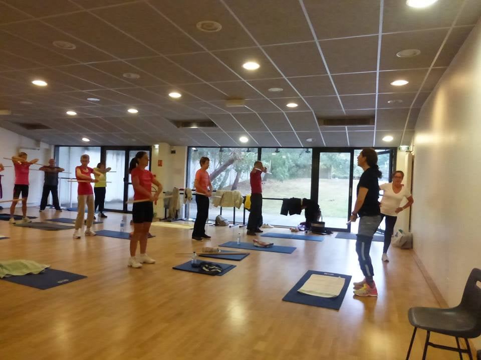 Cours de gym d'entretien dans une grande salle, participants espacés
